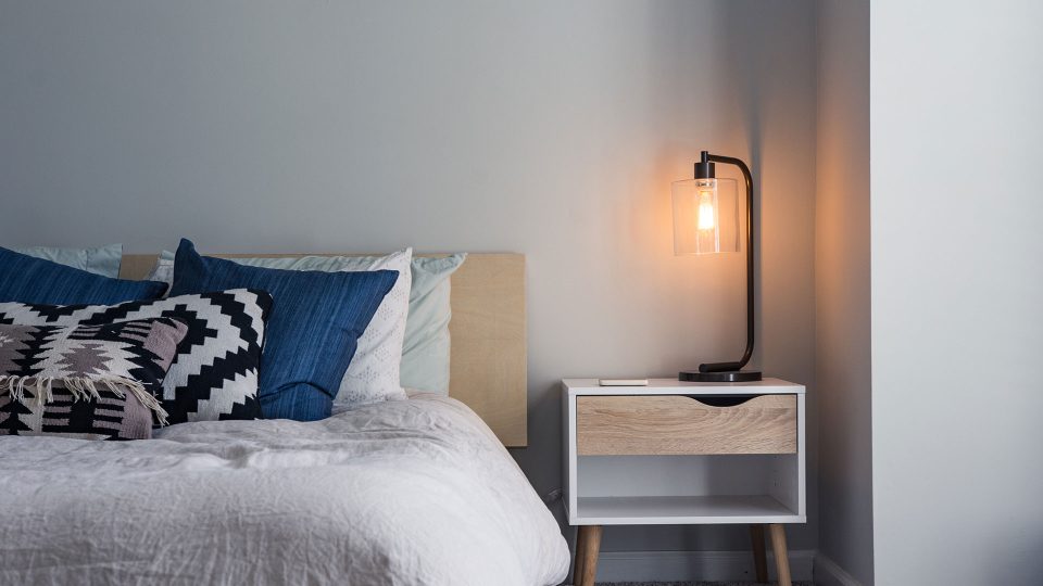 a bedroom with a bed, nightstand and lamp at The  Hargrove at Southpoint