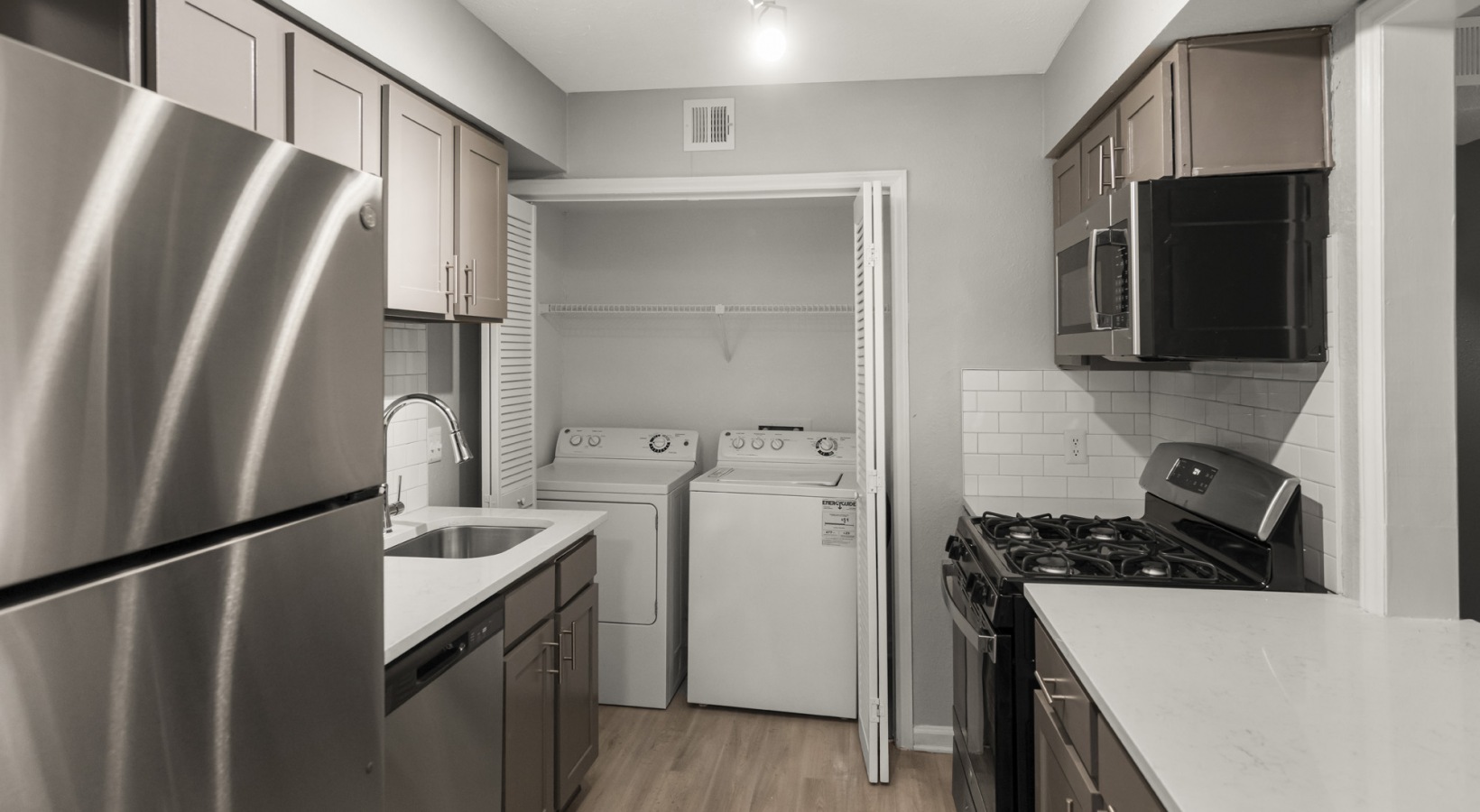 a kitchen with stainless steel appliances and a washer and dryer at The  Hargrove at Southpoint