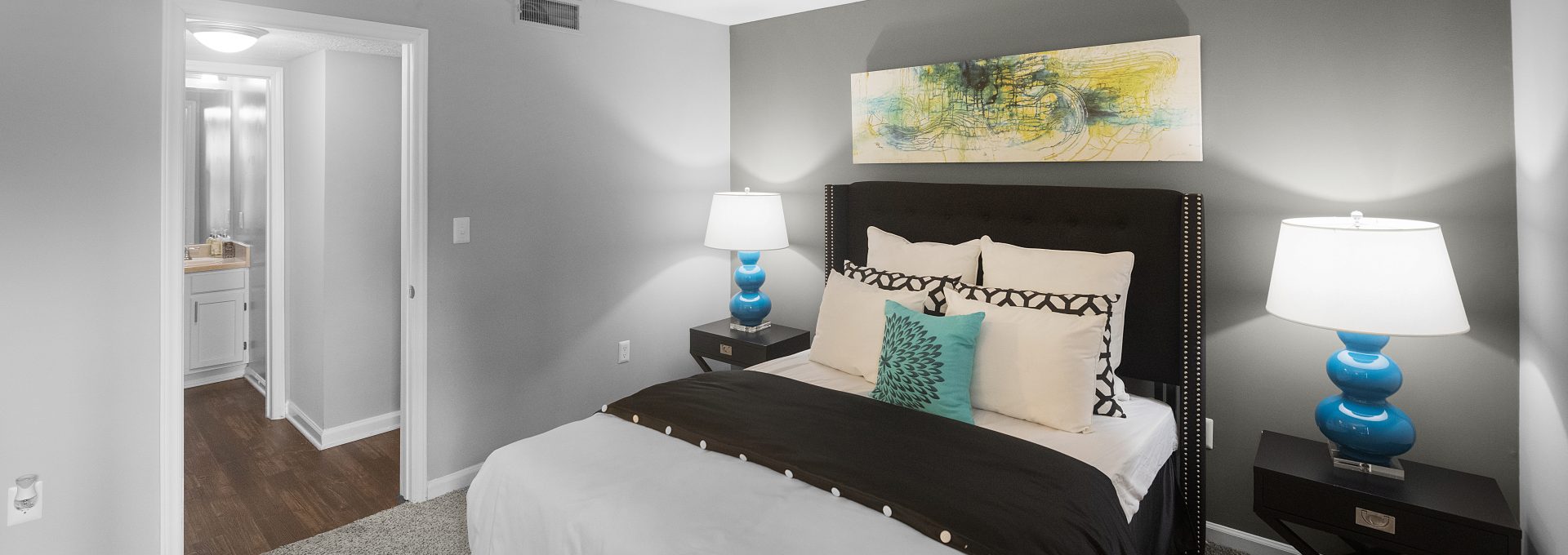 a bedroom with gray walls and a white bed at The  Hargrove at Southpoint