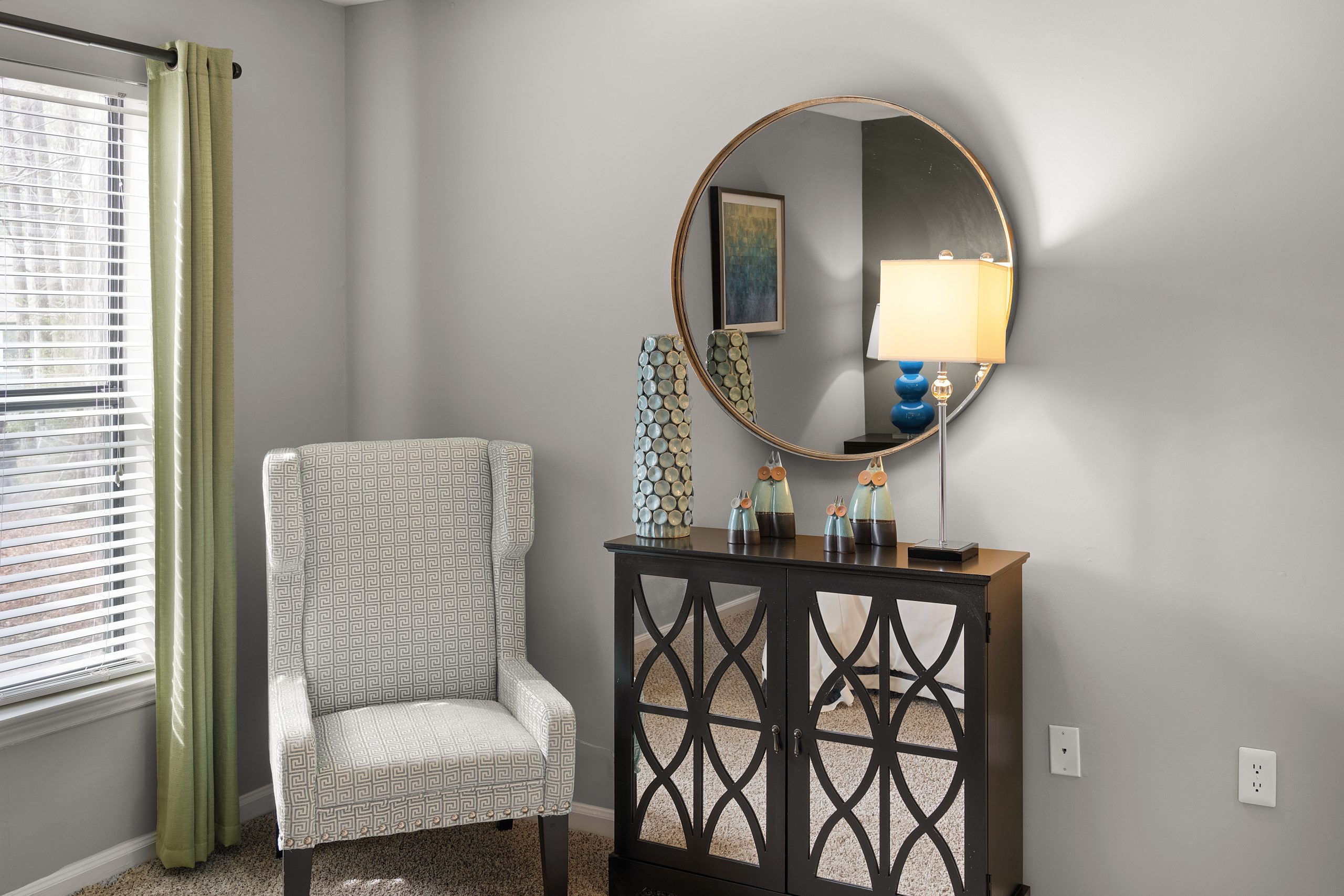 a living room with a mirror and chair at The  Hargrove at Southpoint
