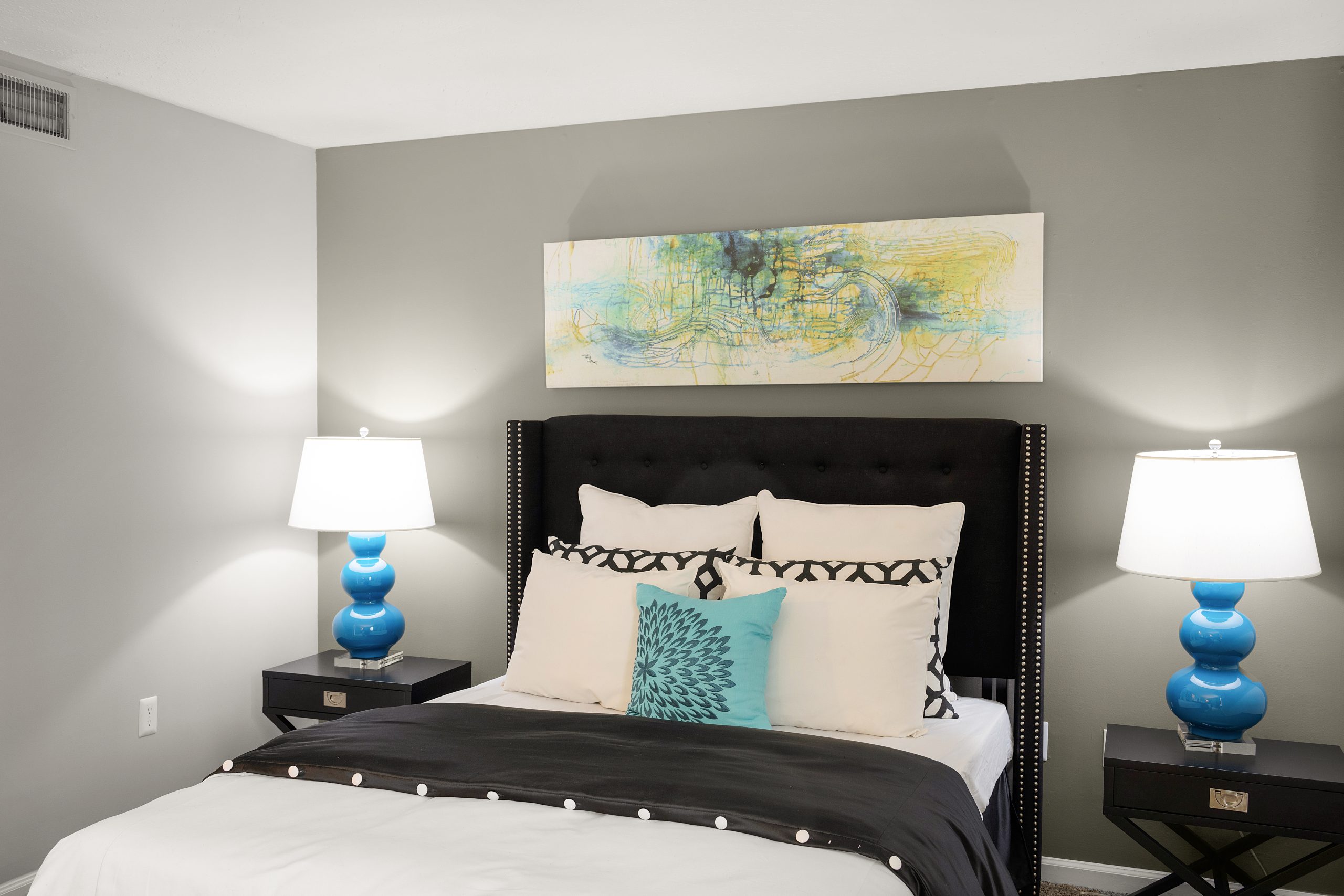 a bedroom with a black and white bed and blue pillows at The  Hargrove at Southpoint