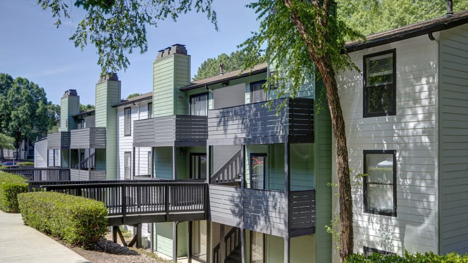 the exterior of an apartment complex with trees and bushes at The  Hargrove at Southpoint